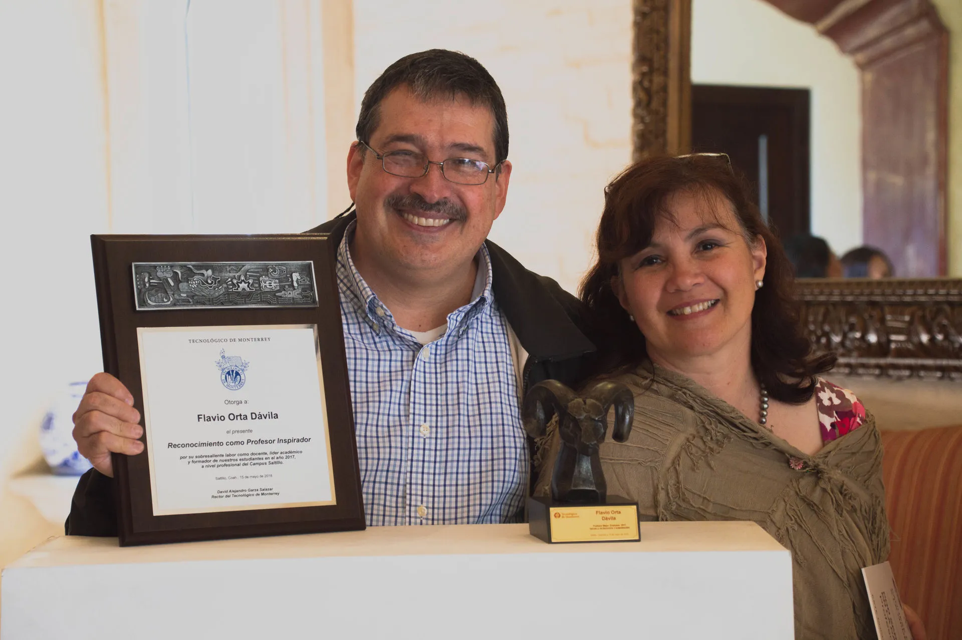Profesor deteniendo reconocimiento junto a su esposa
