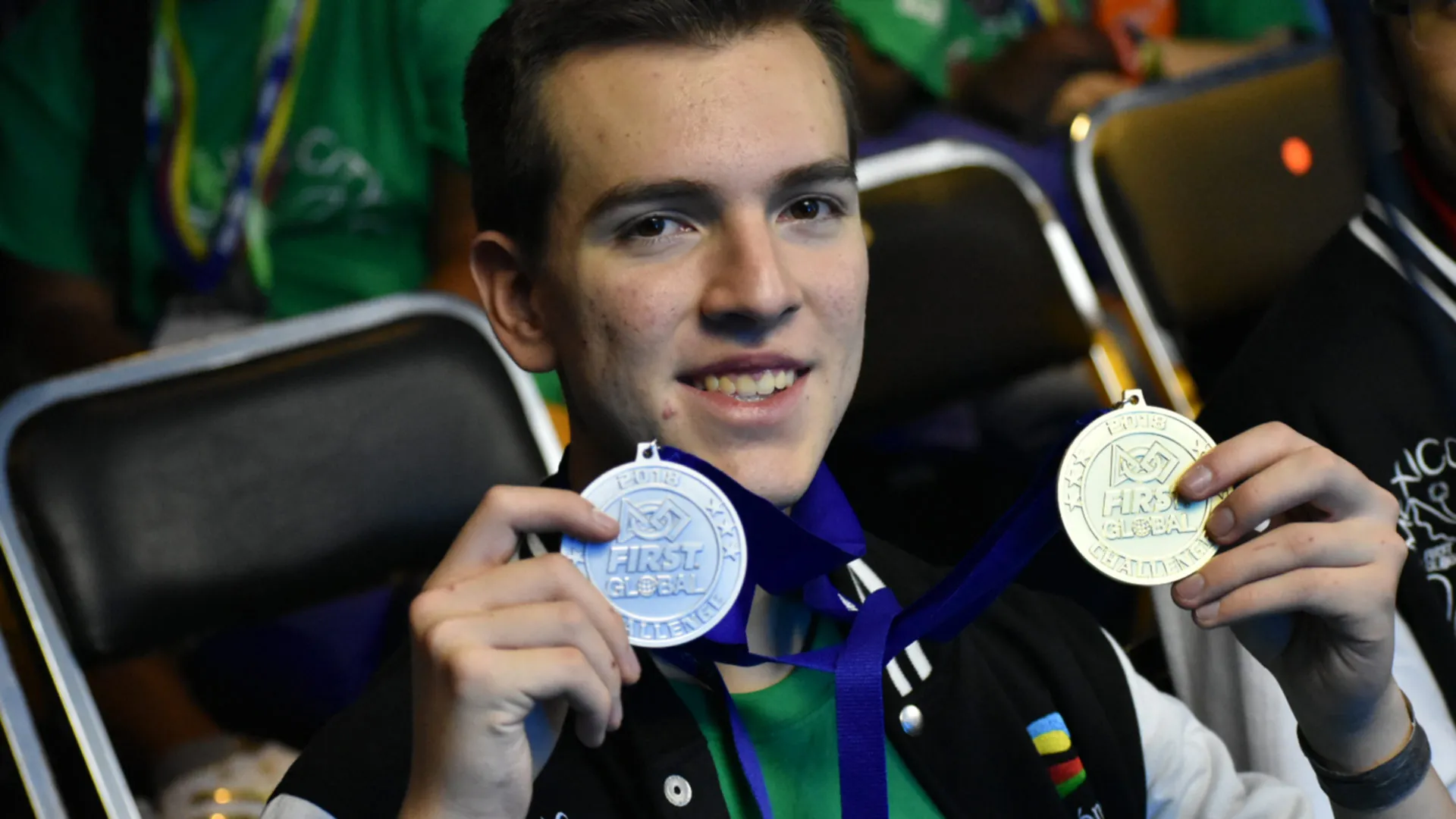 Joven sostiene medalla de oro y bronce mientras sonríe a la cámara