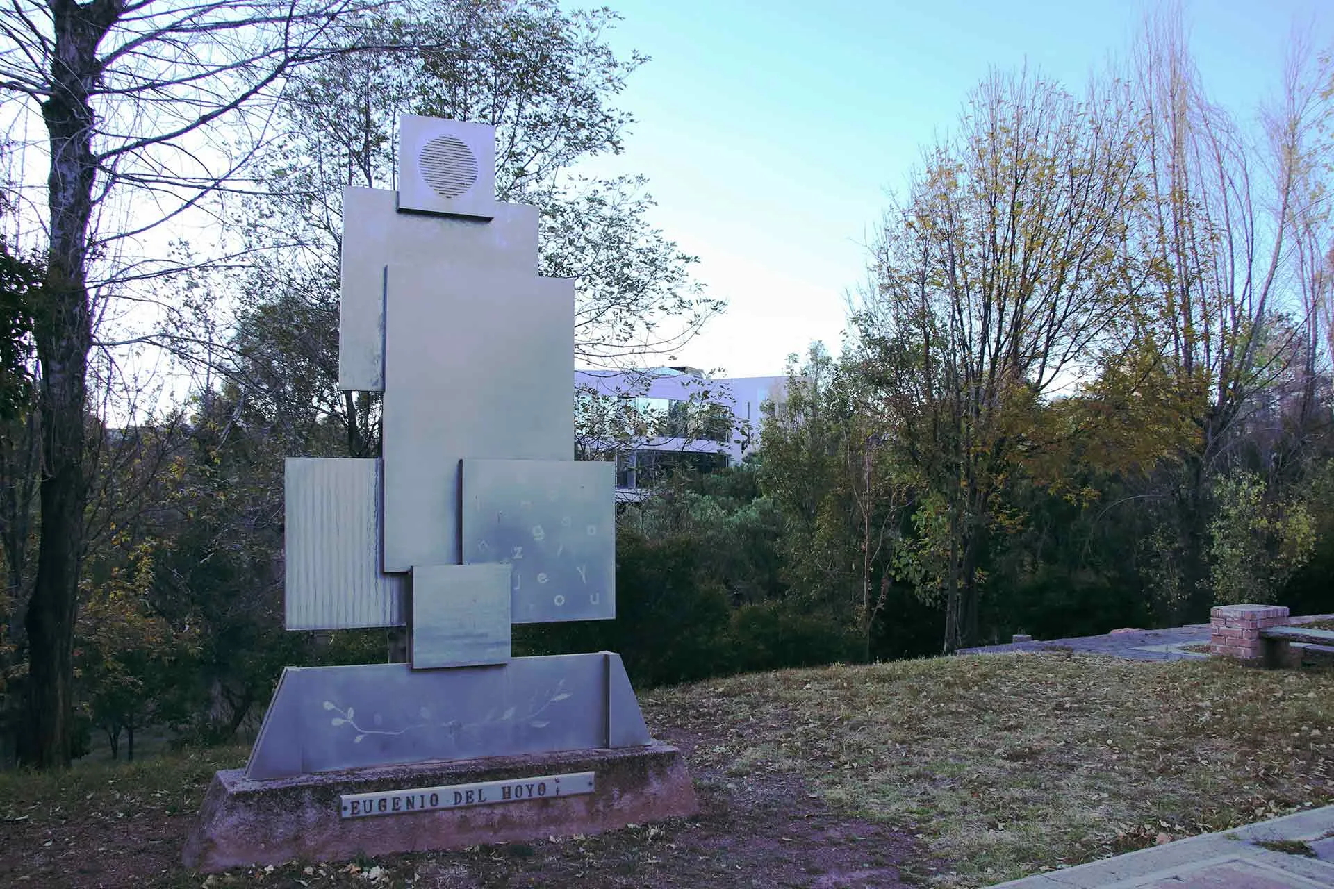 Imagen del monumento en Memoria a Don Eugenio del Hoyo, a un costado de cafeteria, se muestran varias figuras rectangulares, acomodadas una sobre la otra y articuladas verticalmente.