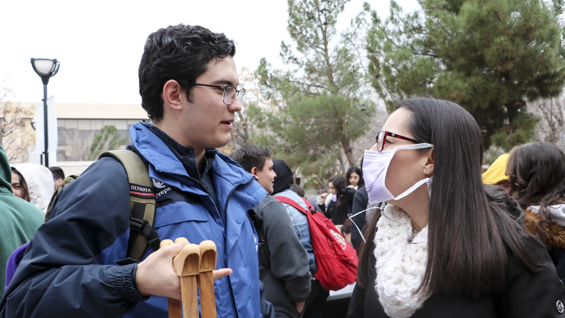 Alumno sosteniendo muletas y maestra con cubre bocas. 