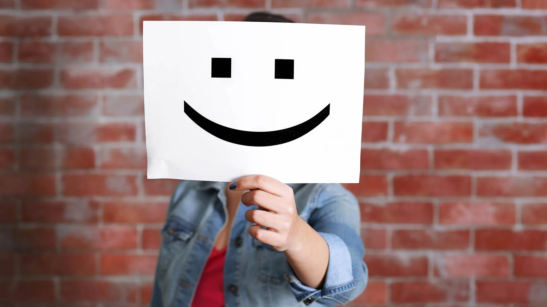 Mujer mostrando una hoja de papel con una carita feliz
