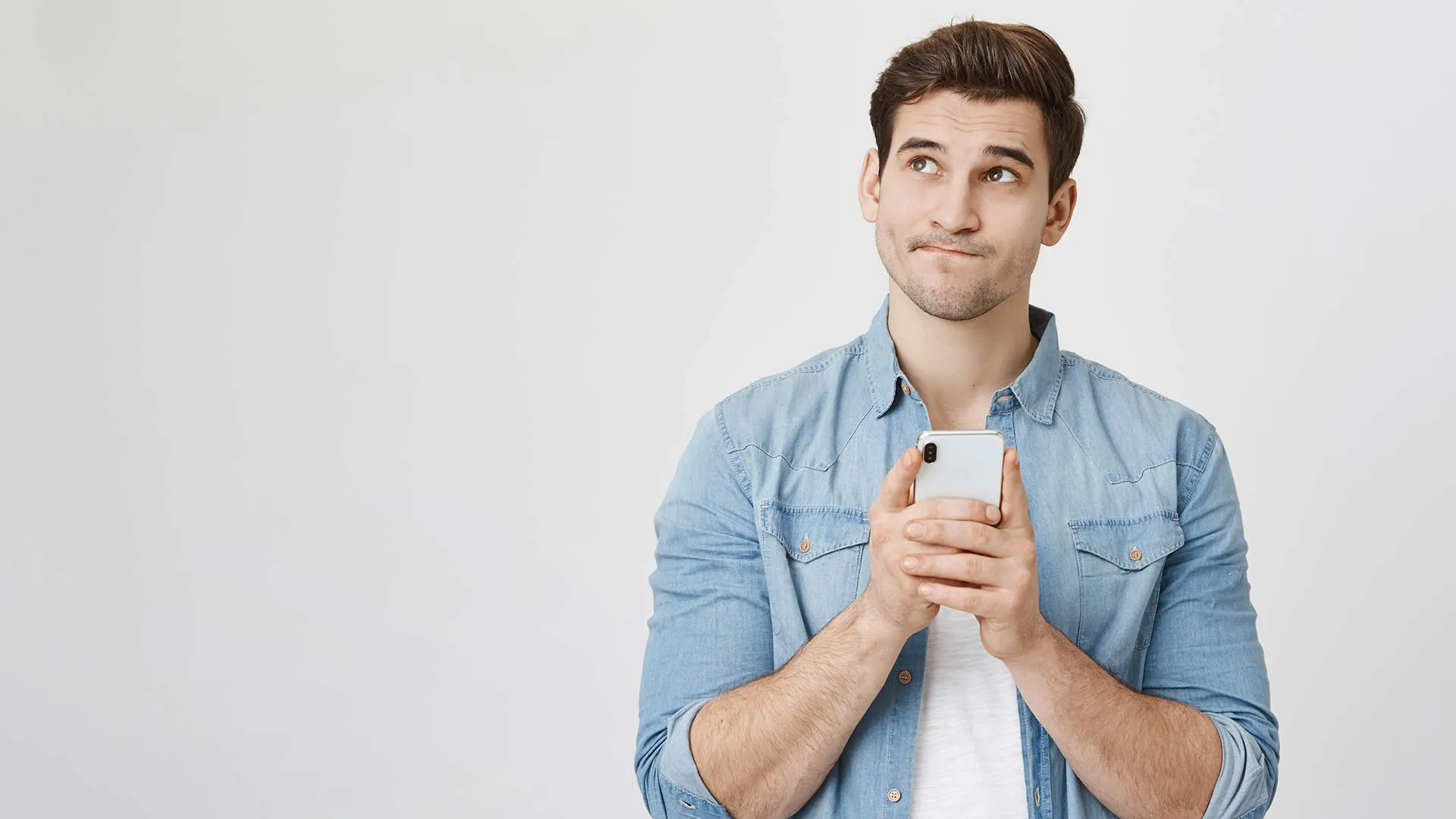 Consejos para no sentirte solo esta cuarentena. En la foto aparece un joven pensativo con su celular en mano