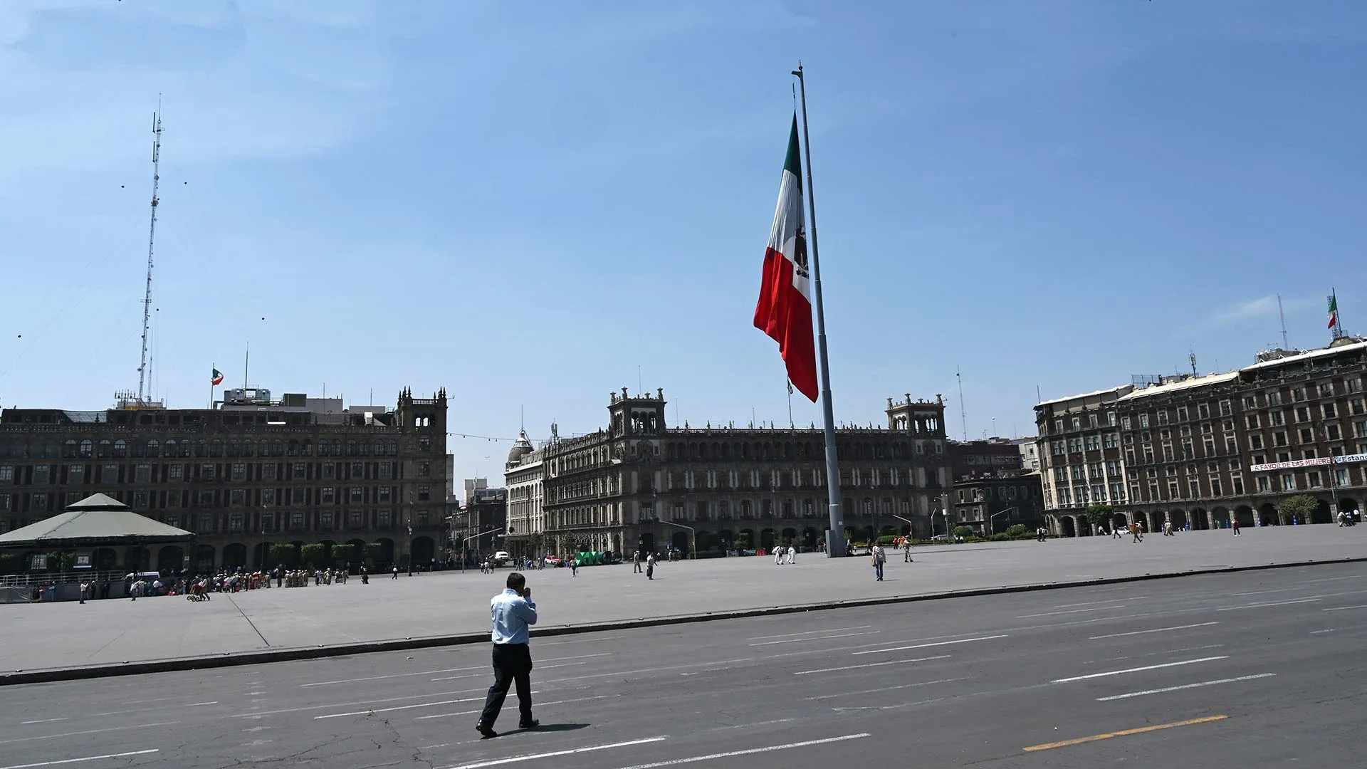 Vista del Zócalo de la Ciudad de México, con una persona caminando por su calle ante el vacío de vehículos