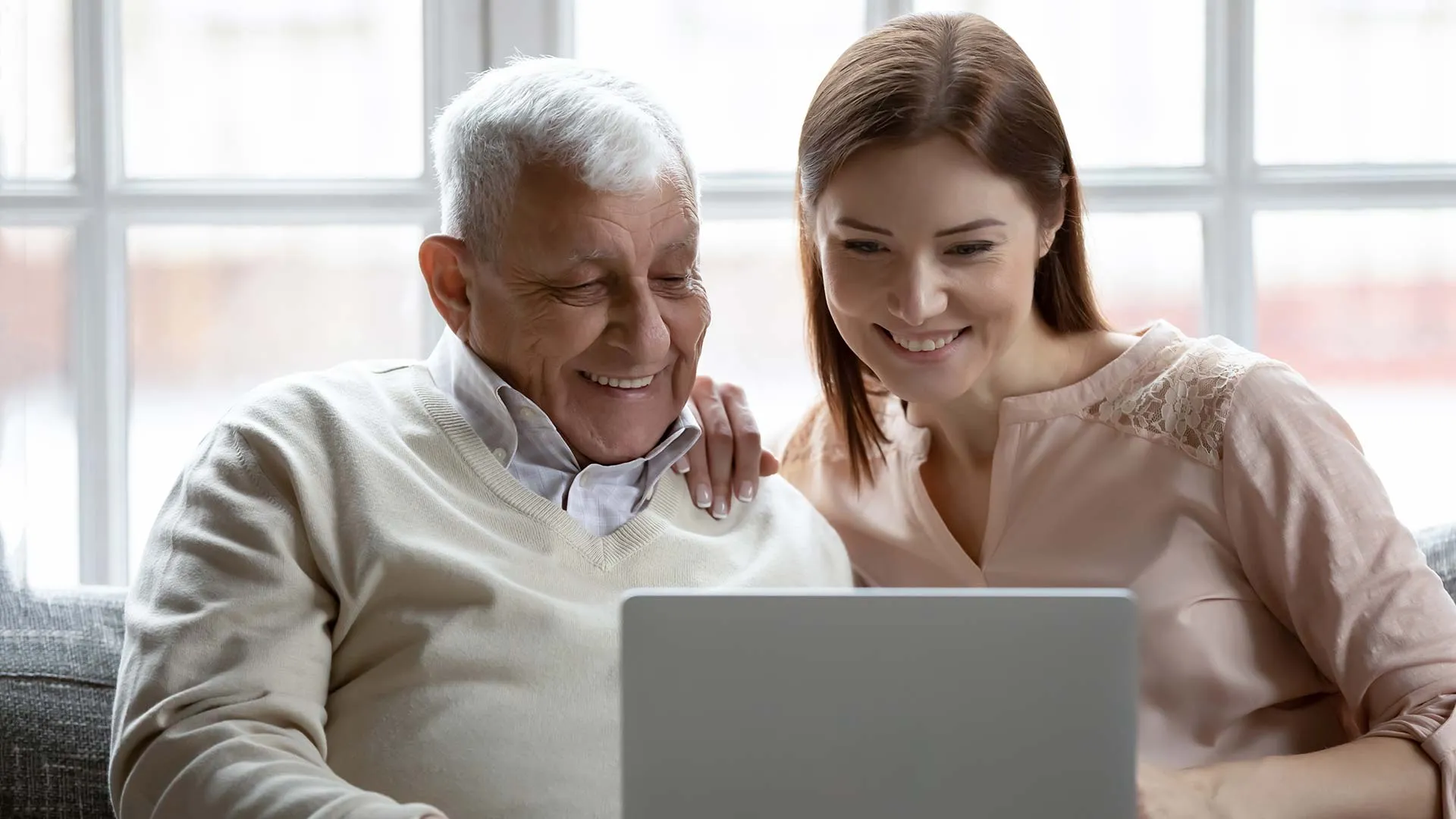 Adulto mayor y mujer joven usando una laptop