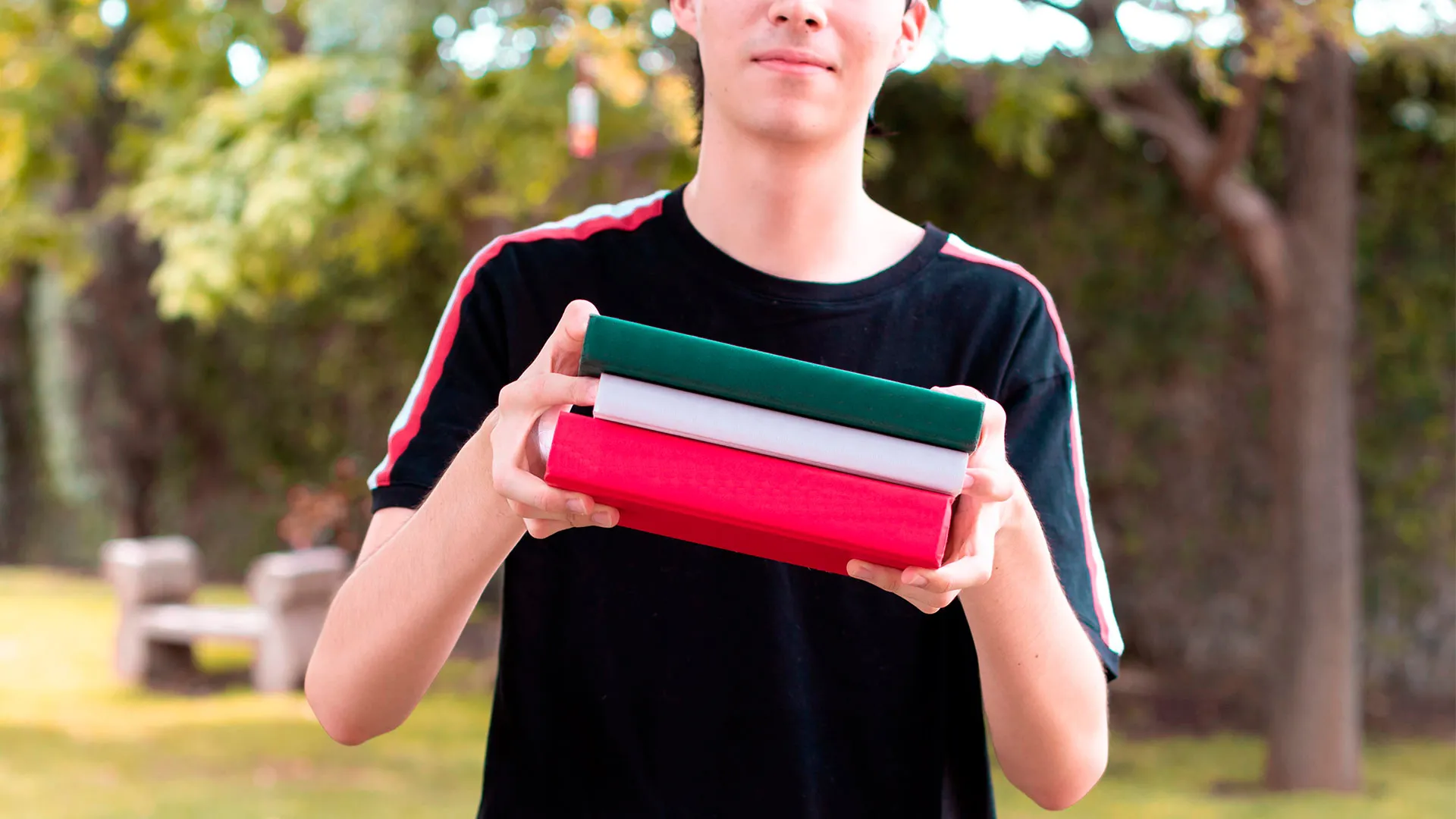 Joven sosteniendo libros verde, blanco y rojo