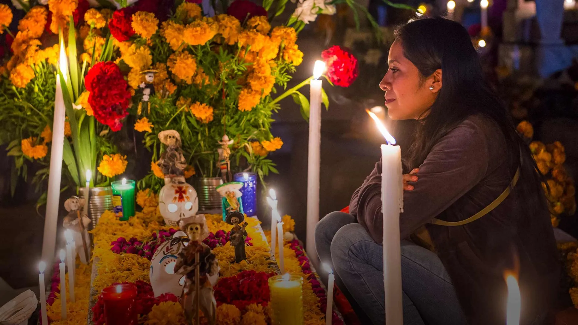 Mujer frente a ofrenda del Día de Muertos