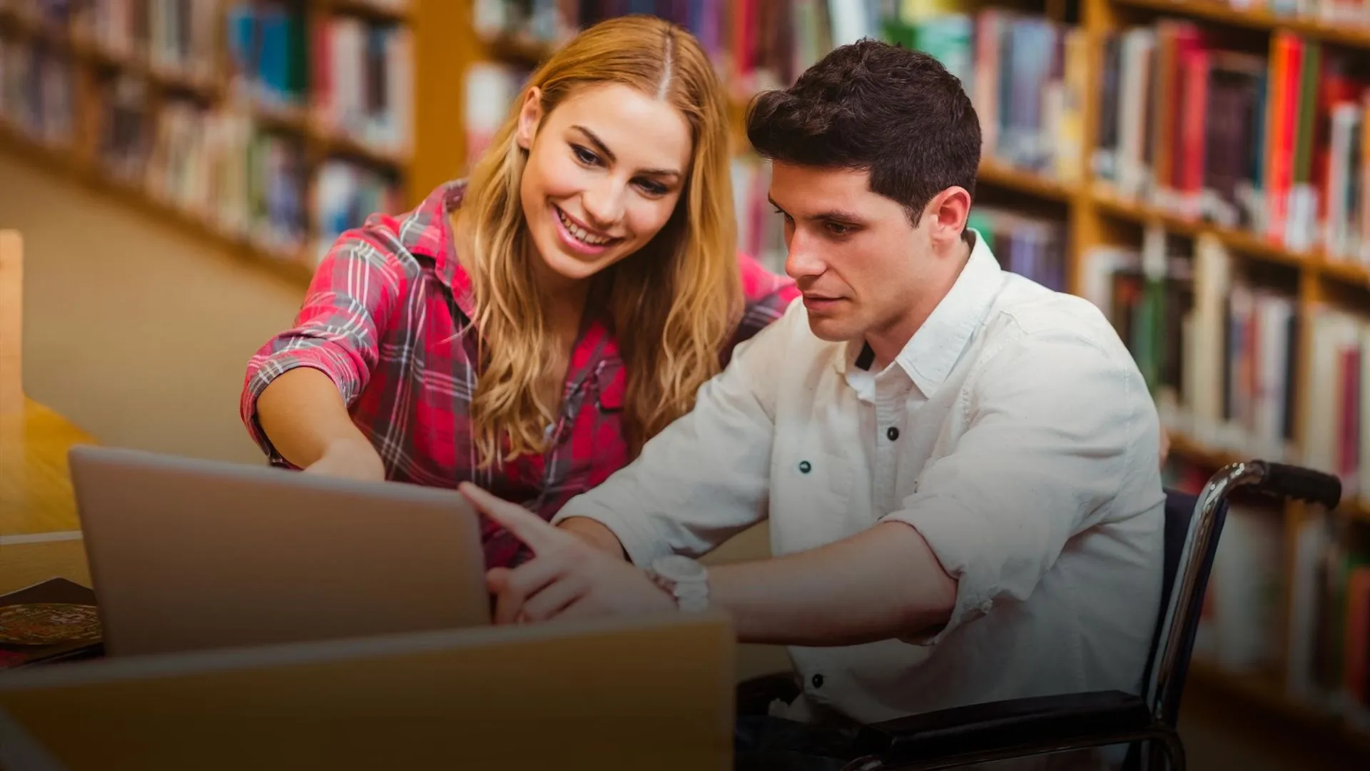 Alumno con discapacidad motriz y estudiante en biblioteca