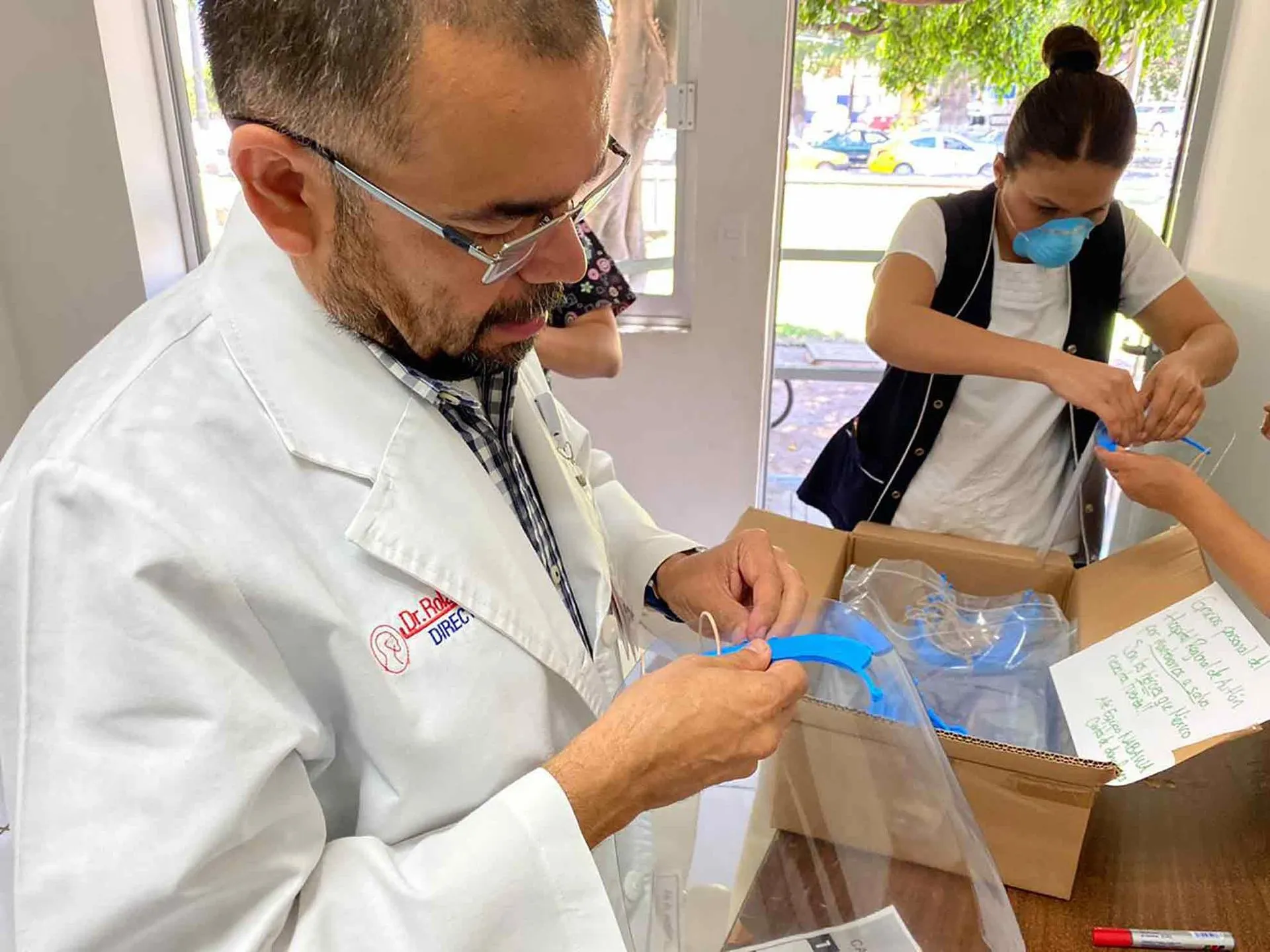 doctor abre paquete de proyecto nabawa de egresados del Tec con caretas médicas para combatir covid19.