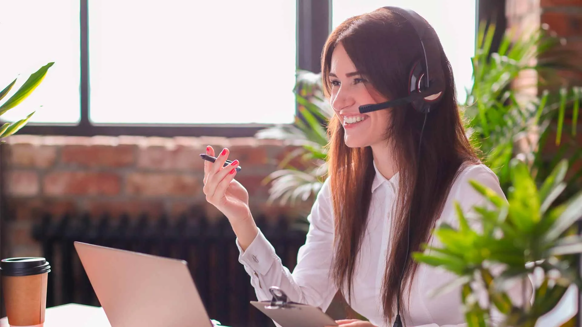 Mujer feliz trabajando en casa con plantas a su alrededor