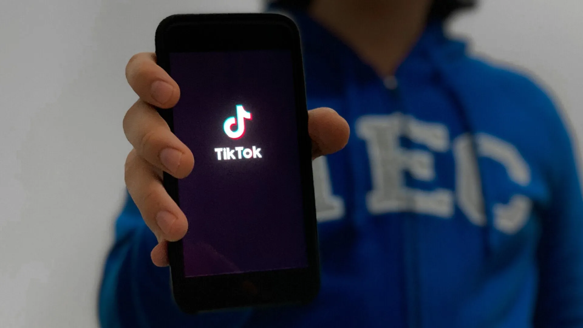 Persona enseñando su celular con la pantalla de inicio de la aplicación de TikTok.