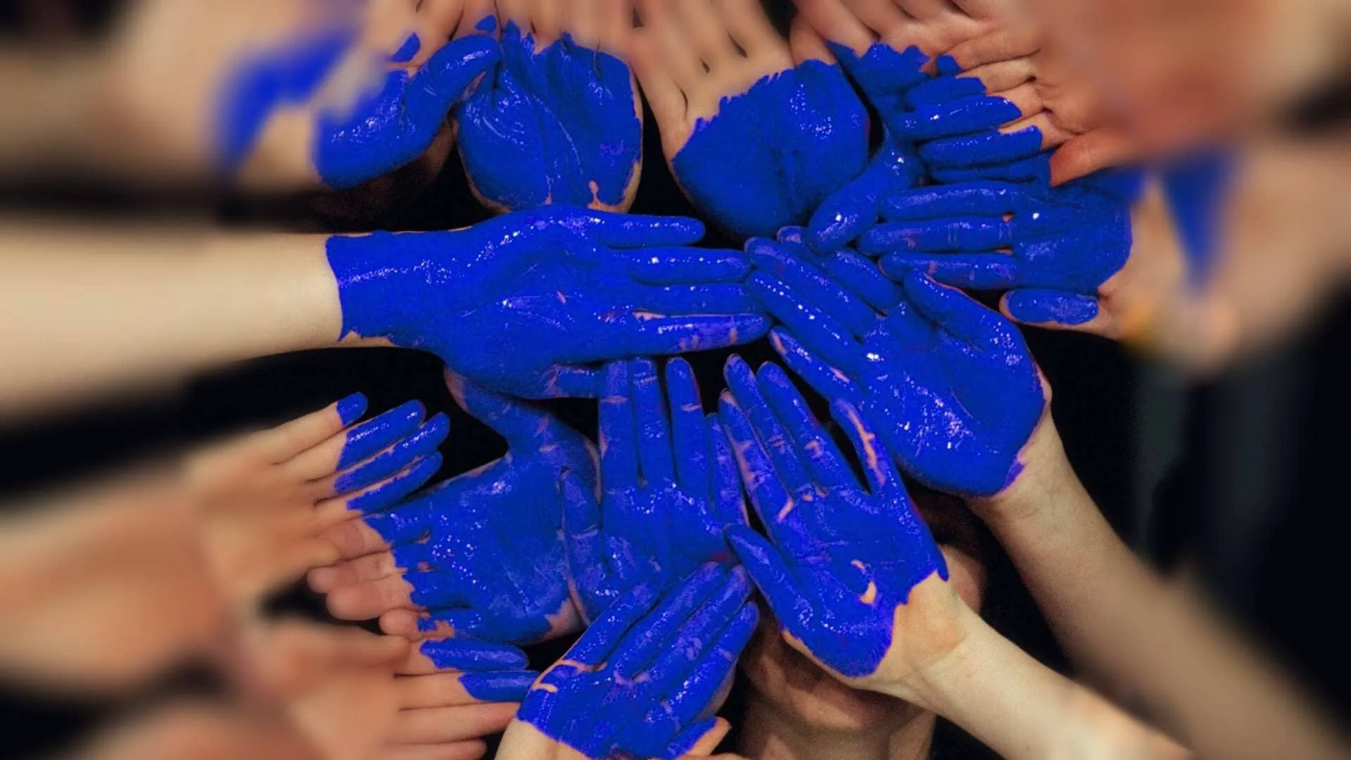 Alumnos de PrepaTec formando un corazón con sus manos pintadas de azul.
