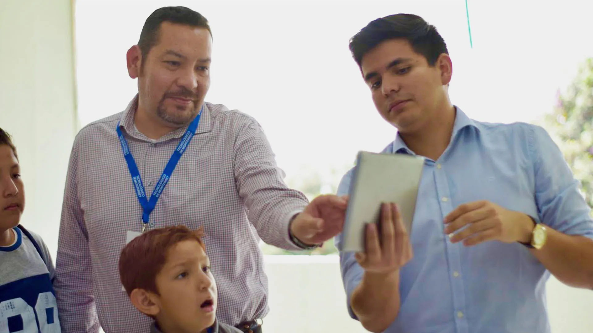 alumno del Tec presentando su proyecto de ingeniería a niños y a un profesor.
