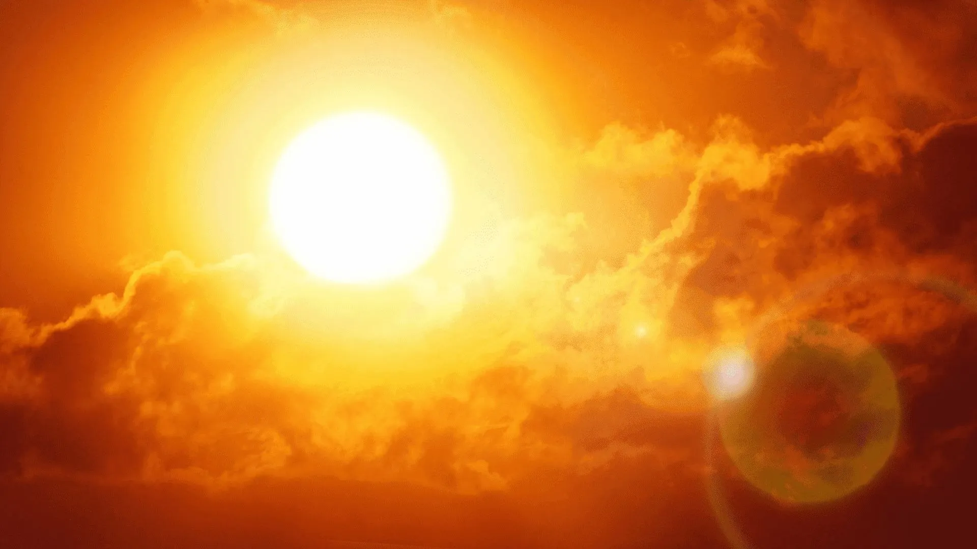 Fotografía del sol reflejando sus rayos en el cielo con tonalidades rojizas/naranjas por altas temperaturas.