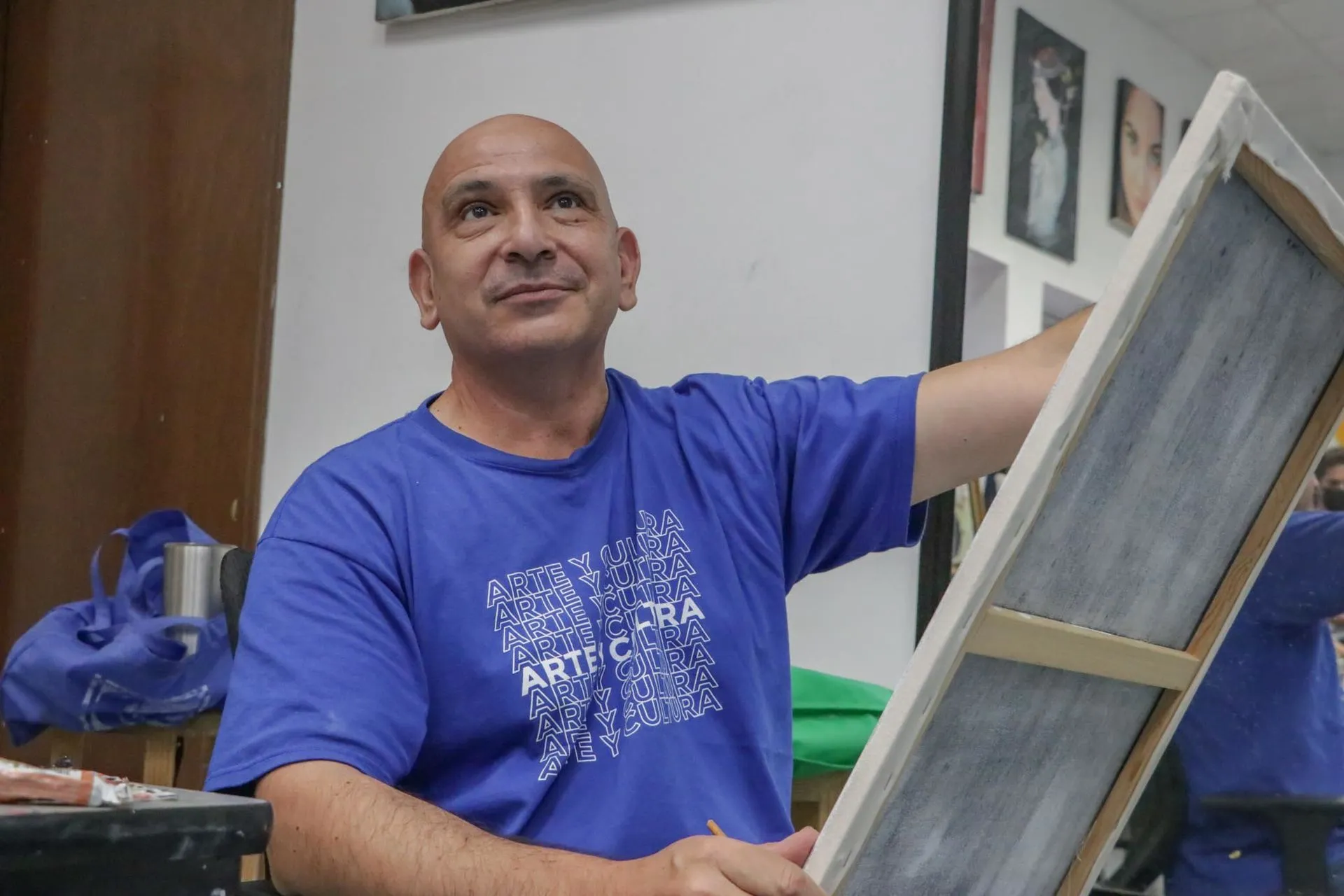 Profesor de artes plásticas pintando un cuadro con ligera sonrisa volteando hacia arriba.
