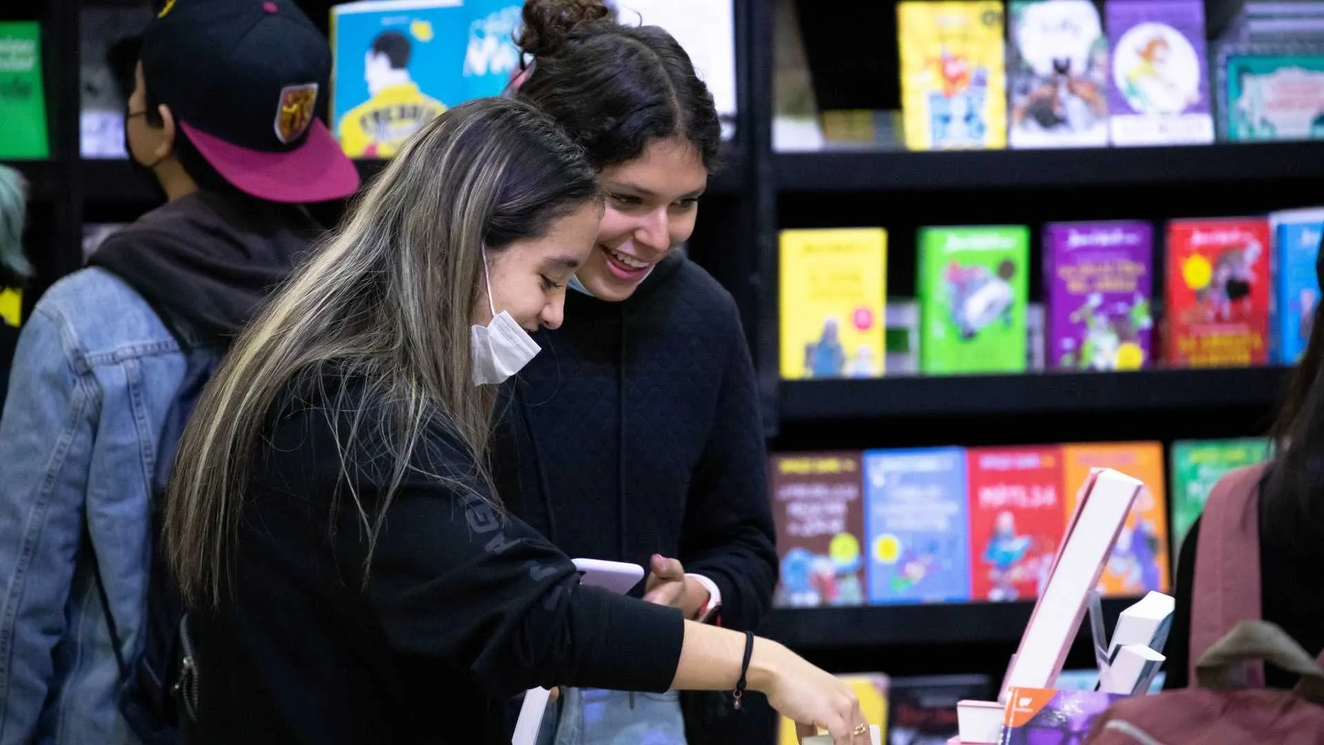 Dos mujeres jóvenes buscan libros en la FIL Monterrey 2022