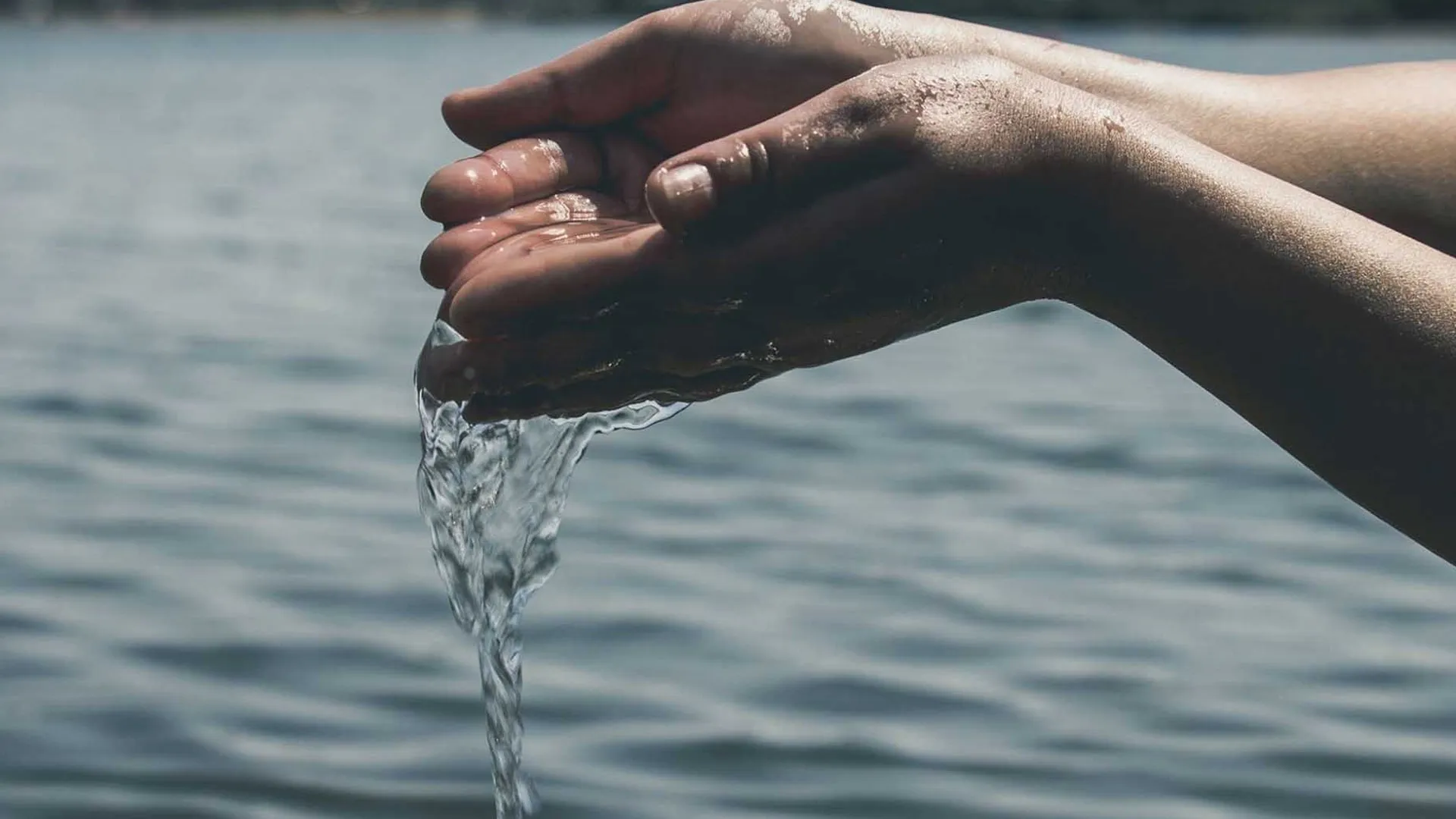 Manos agarrando agua y dejándola caer. 