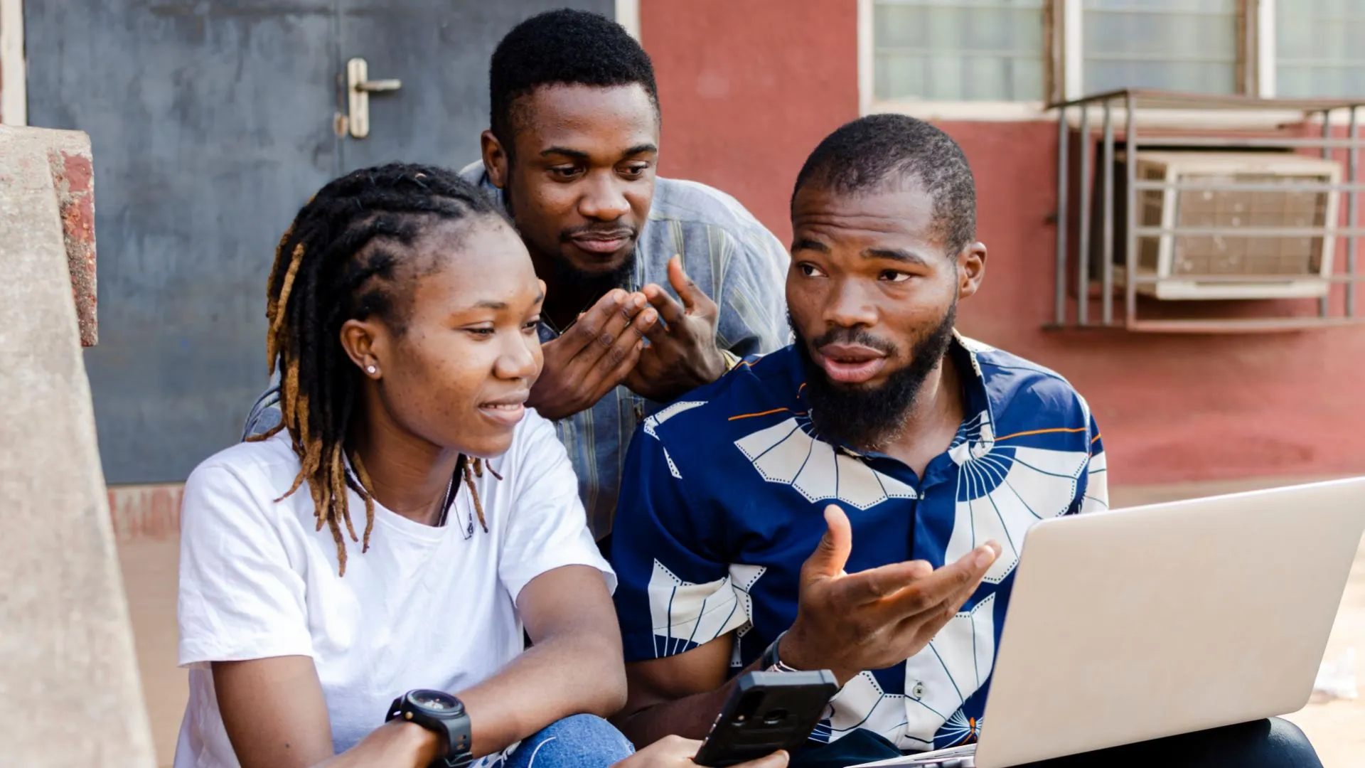 2 jóvenes y 1 chica africana, observando una laptop.