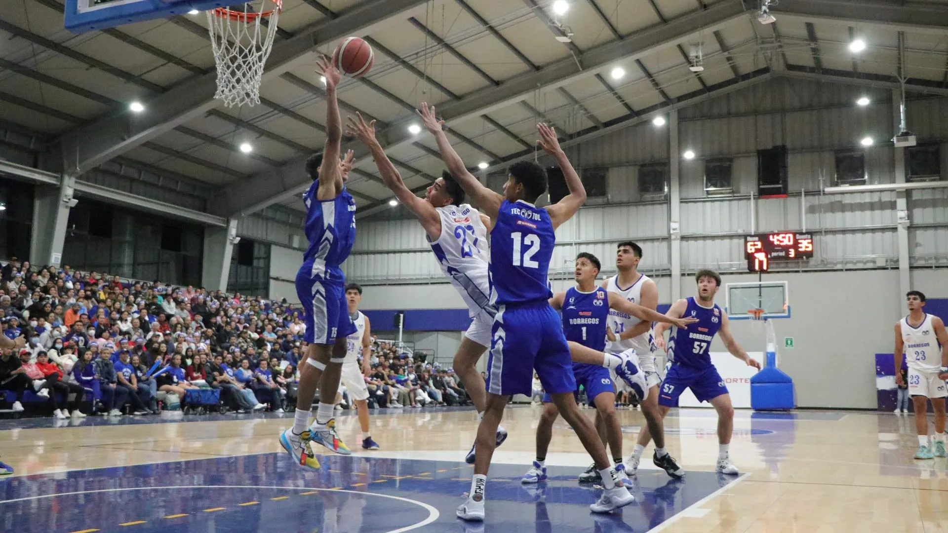 Ricardo Maciel, jugador de Borregos Hidalgo realizando una colada en medio de 2 jugadores.