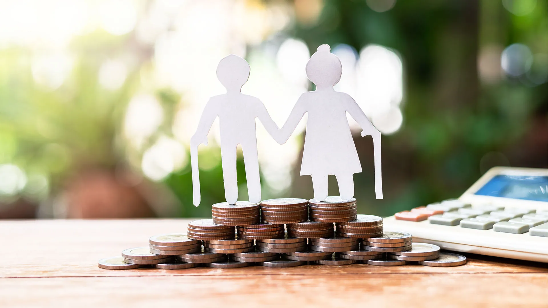 Foto conceptual de una pareja de personas de la tercera edad, sobre monedas, conceptualizando su pensión para el retiro