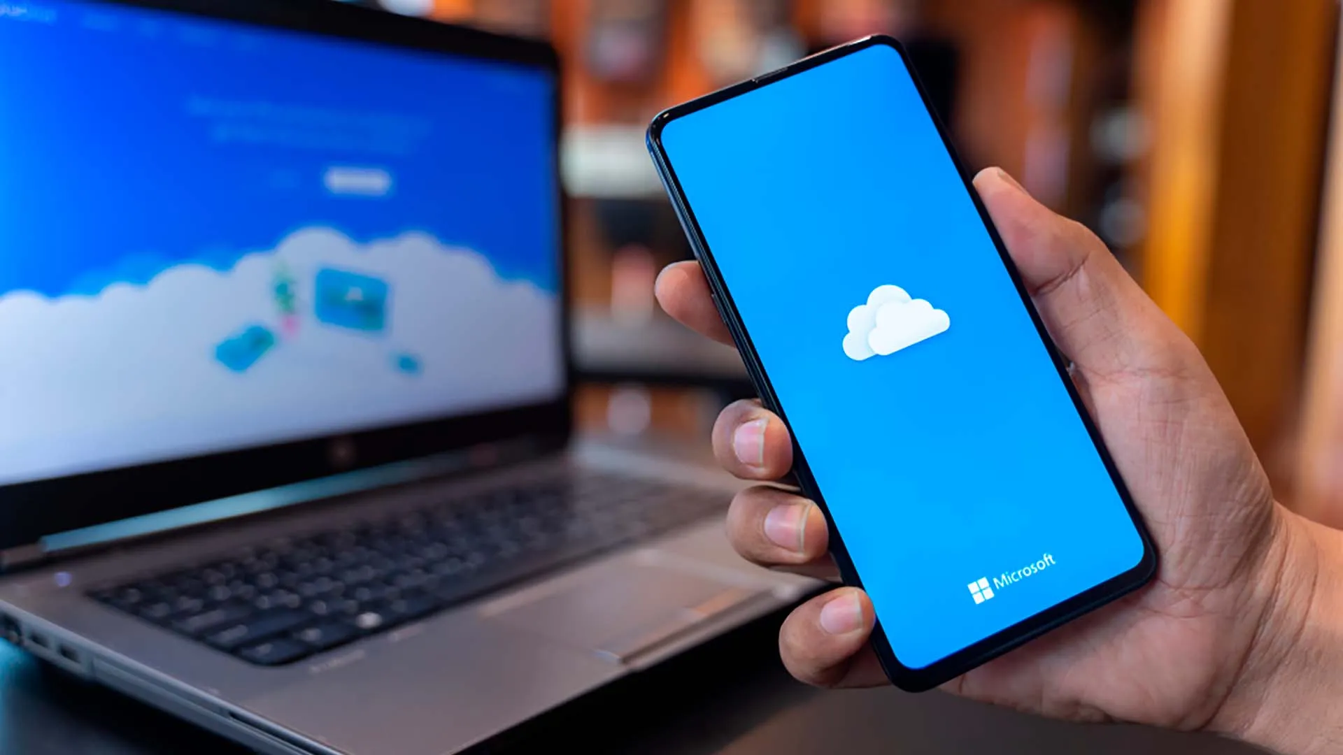 Celular y computadora con el logo de la herramienta OneDrive
