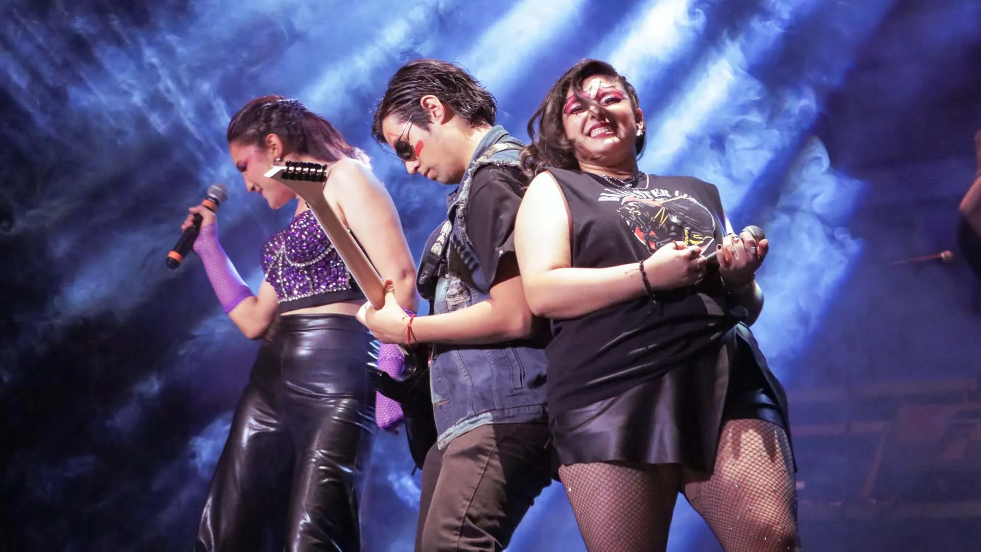 Alumno tocando la guitarra con una cantante a cada lado en poses rockeras como parte del Ensamble IMMORTALITY.