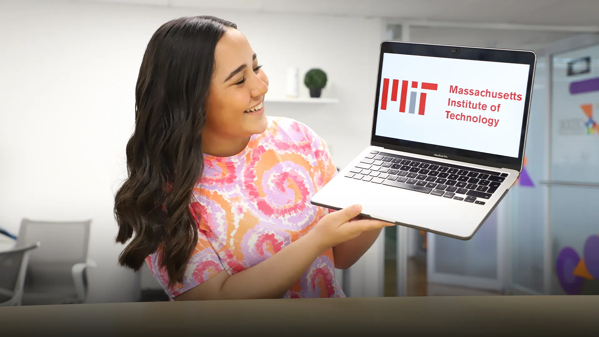 María Guadalupe Córdova sostiene en sus manos una computadora que muestra en pantalla el logo del MIT.
