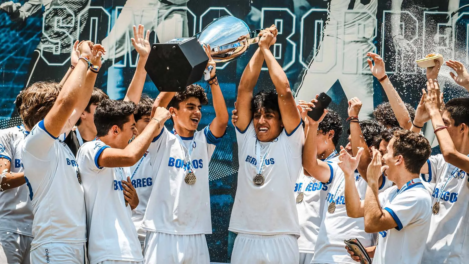 Jugadores de futbol soccer de Borregos Laguna juvenil festejan y levantan un trofeo