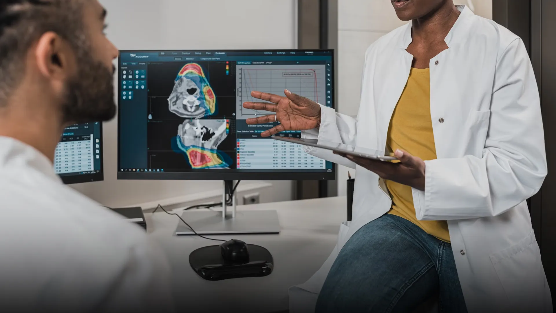 Médicos hablando frente a dos monitores mostrando imágenes médicas.