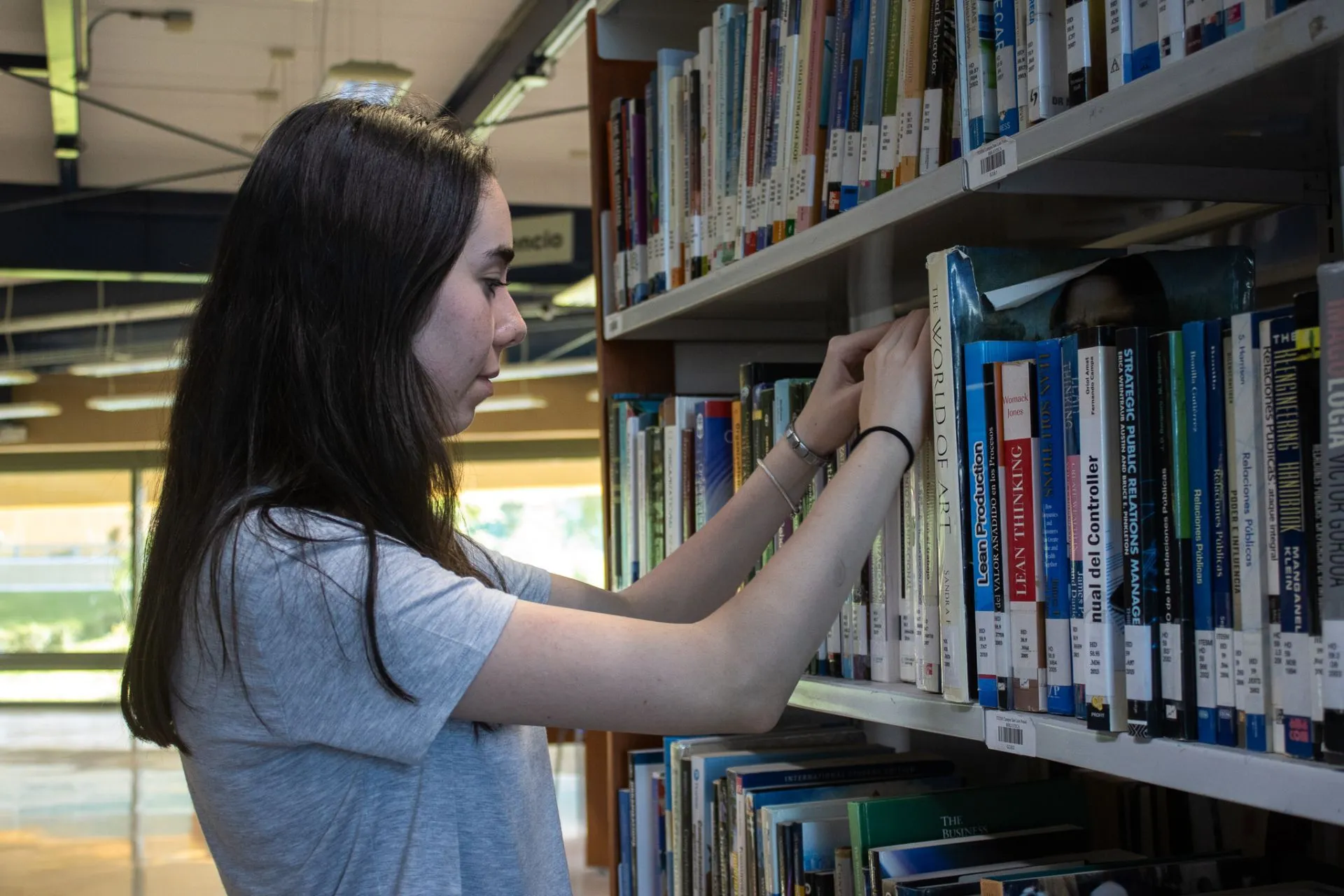 Lucía Oria, ganadora de la beca, busca entre libros en la biblioteca 