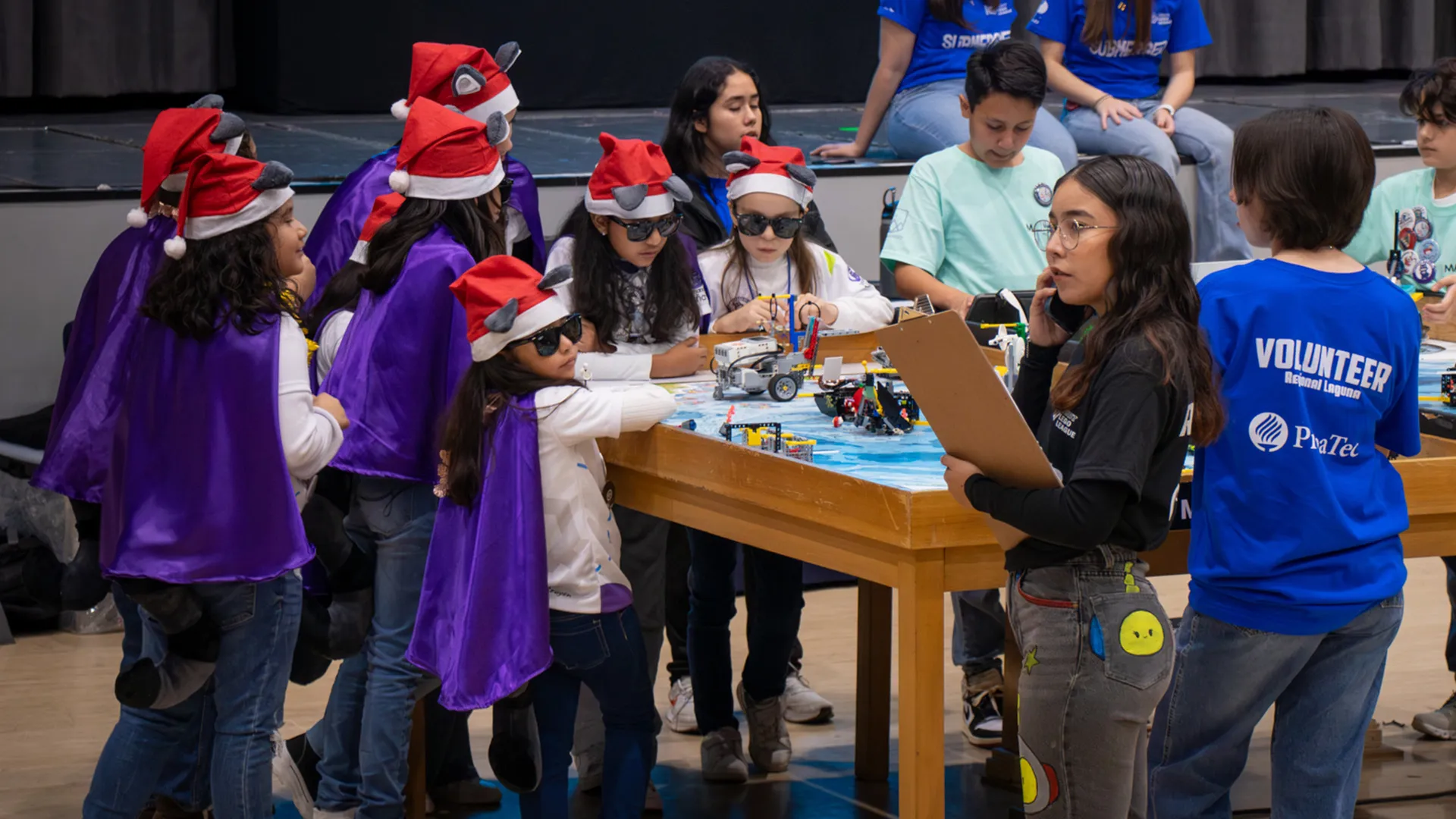 Niñas con gorro navideño y lentes participan en el juego del robot de FIRST LEGO League en PrepaTec Laguna