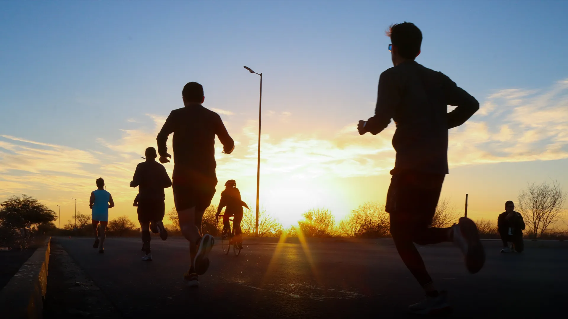 Personas corriendo a contraluz con el amanecer en el fondo