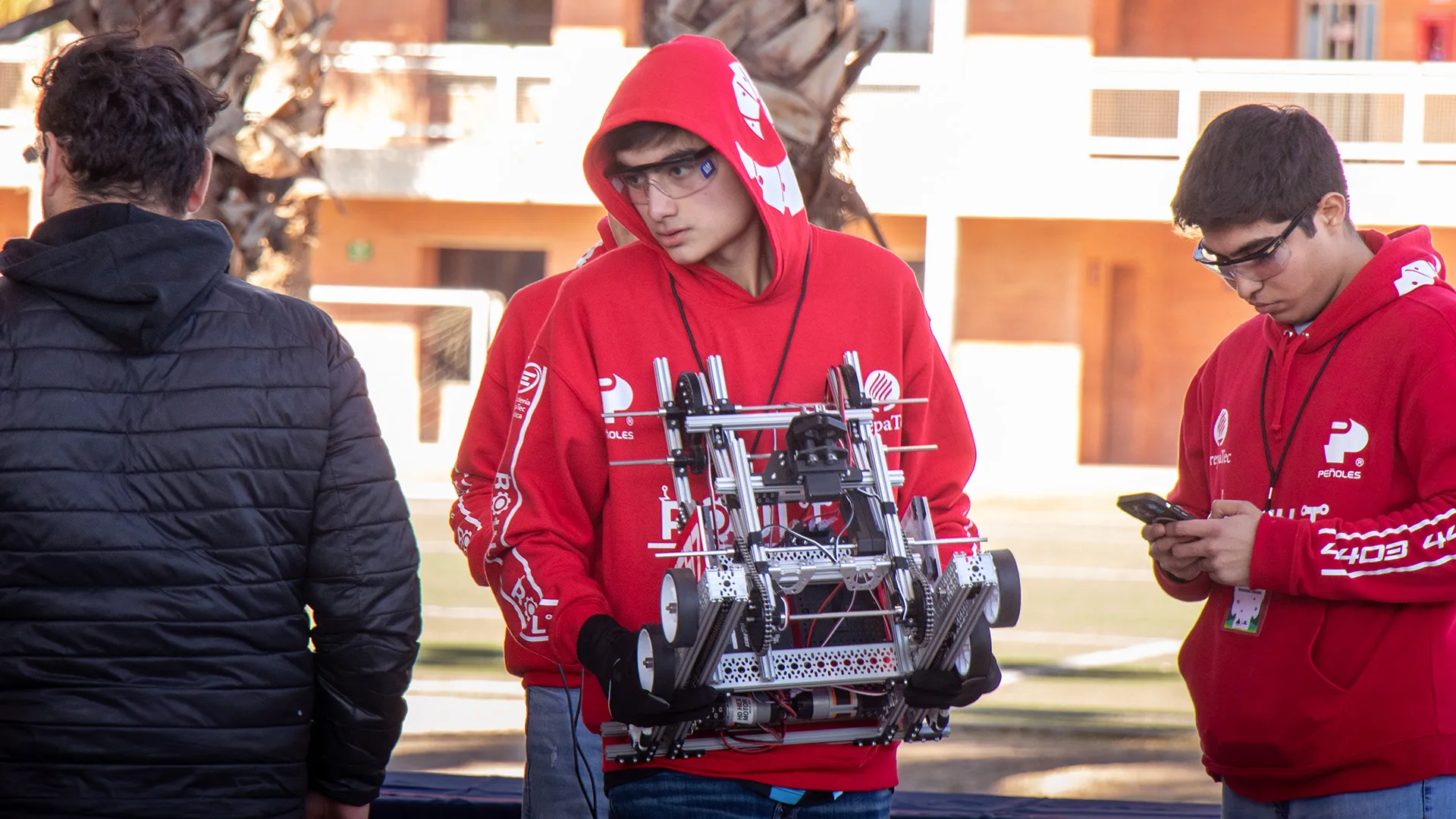 Estudiante joven lleva robot en sus manos en su participación en competencia de robótica