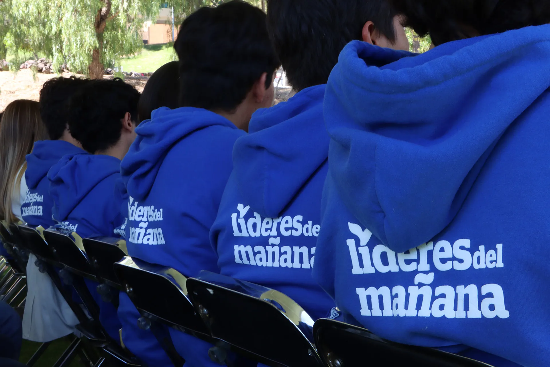 Estudiantes beneficiarios de becas de espaldas en evento