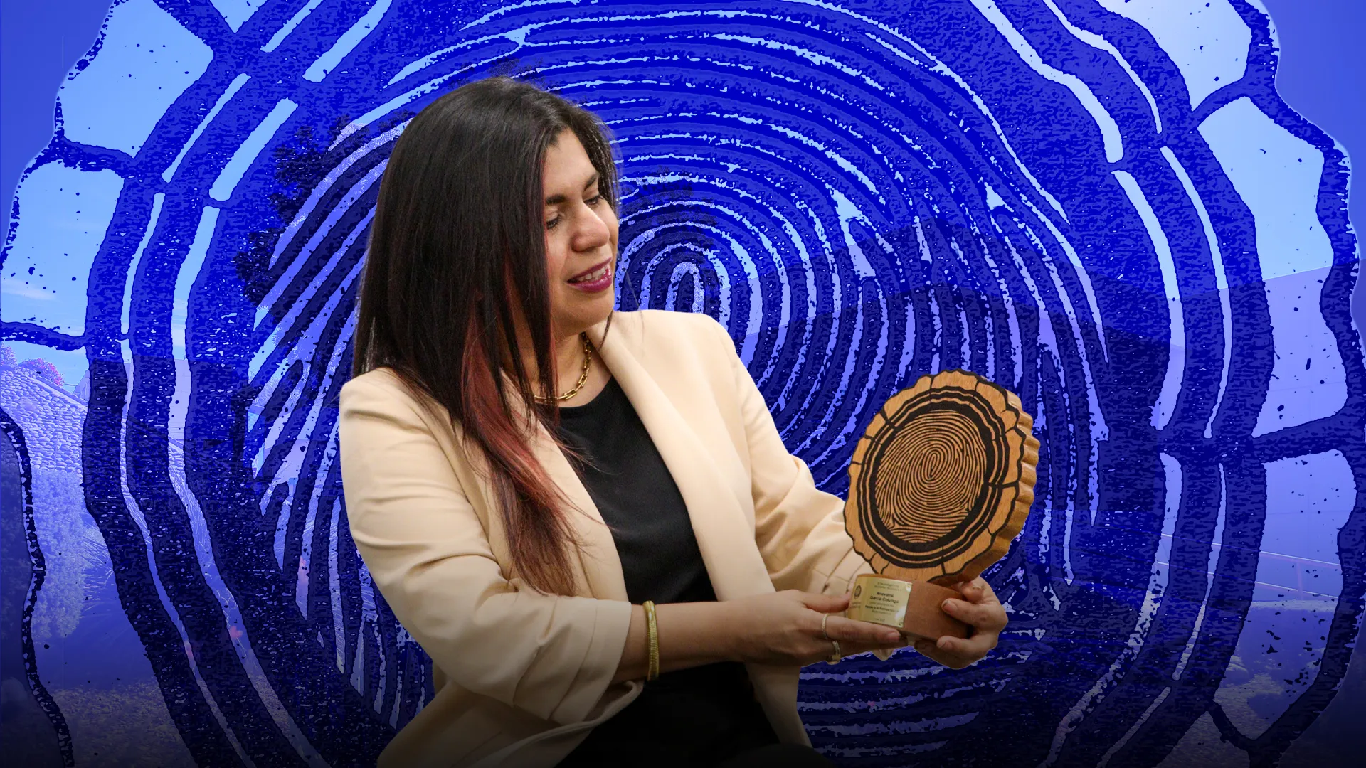 Mujer con saco blanco sosteniendo trofeo con forma de corte transversal de tronco y mirando hacia el.