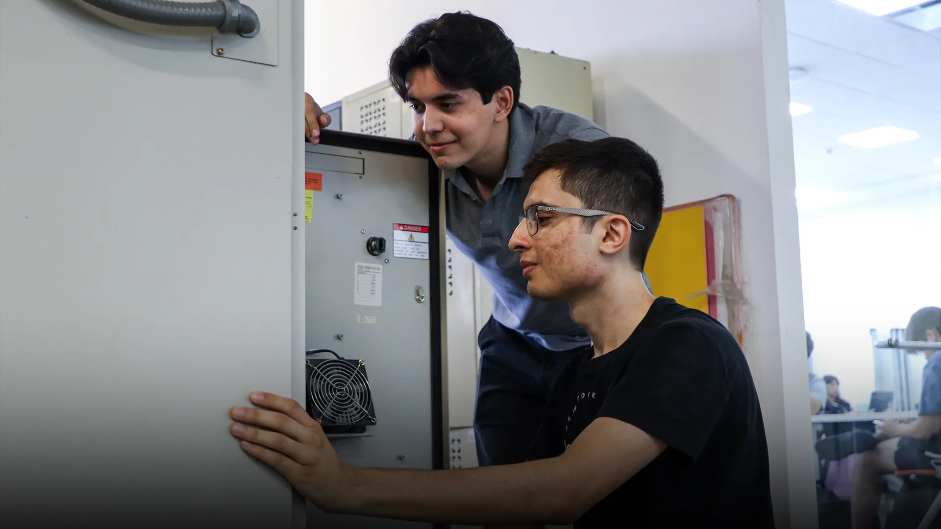 Dos estudiantes analizan los circuitos de una caja.