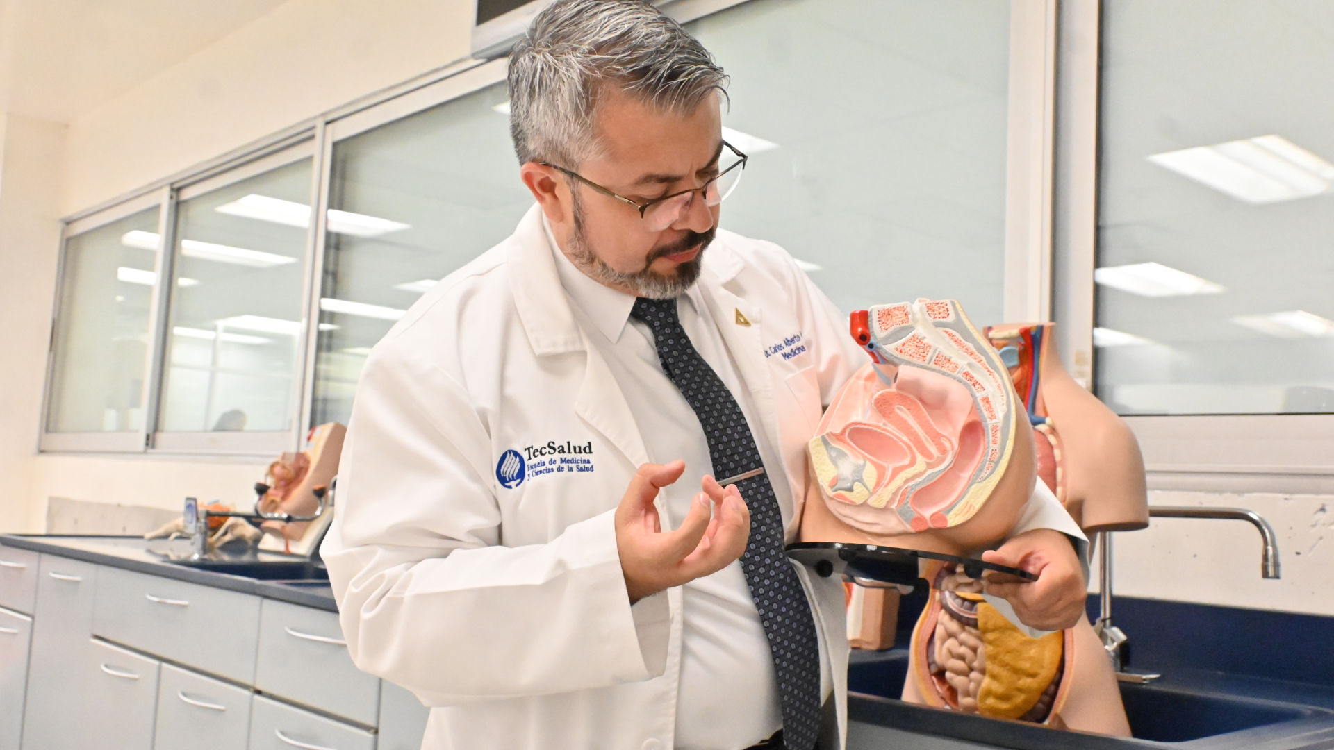Doctor Carlos Moreno sosteniendo un modelo anat&oacute;mico humano