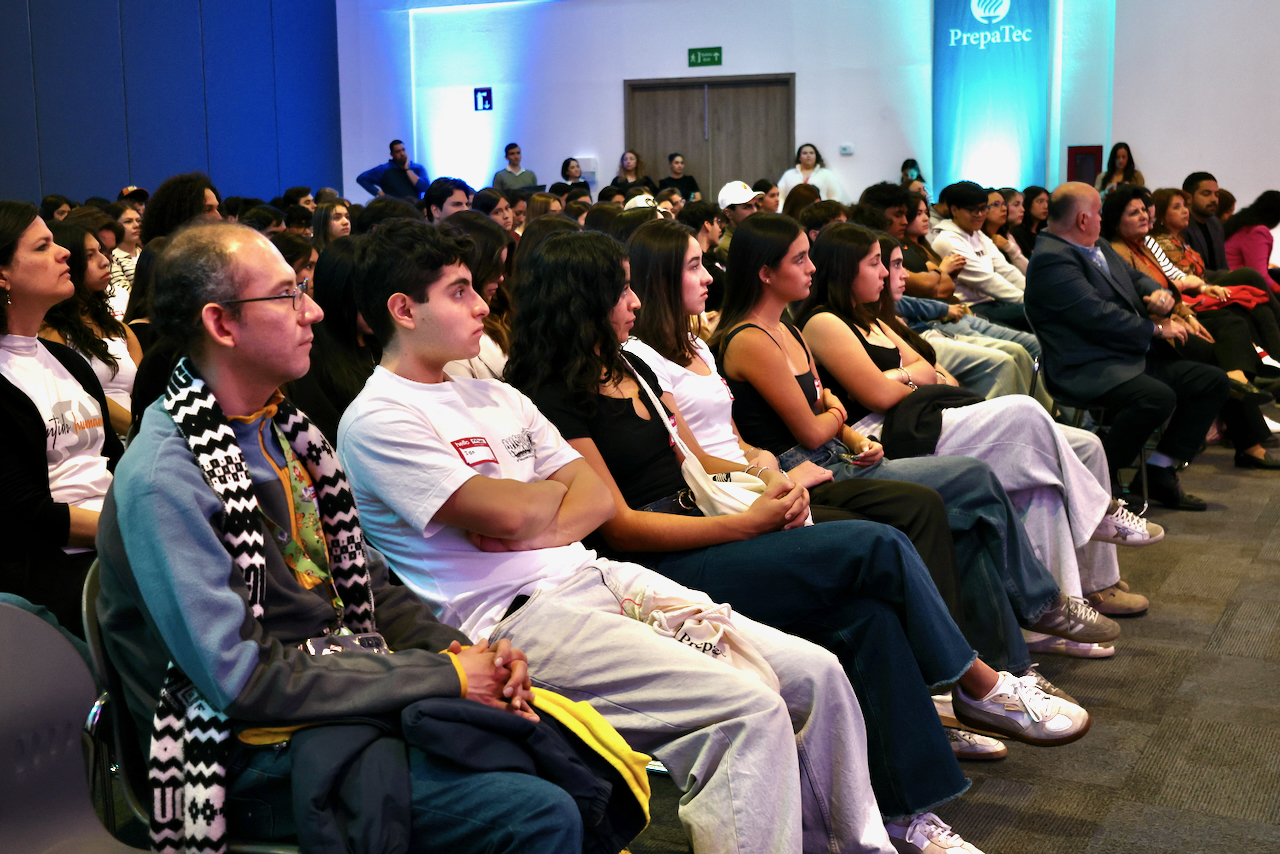 Auditorio lleno de estudiantes de PrepaTec sentados y atentos durante una conferencia del Encuentro Nacional de Líderes con Sentido Humano. La imagen muestra filas de jóvenes escuchando una charla en un espacio iluminado, como parte de las actividades formativas del evento.