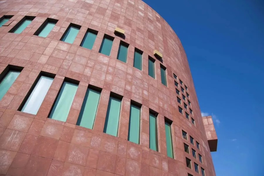 Vista de la fachada de un edificio de la EGADE Business School, con arquitectura contempor&aacute;nea de color rojizo y ventanas verticales, bajo un cielo despejado.