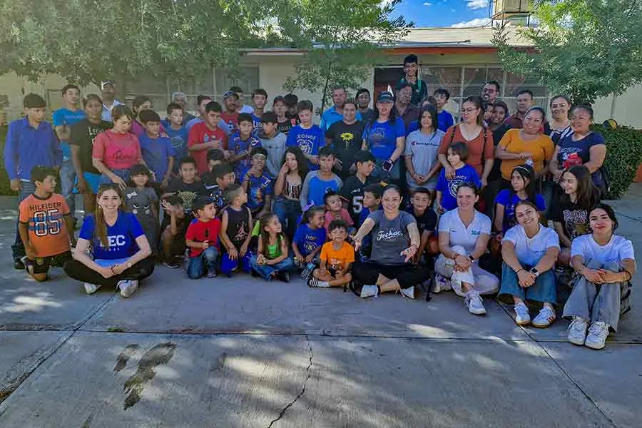 Grupo de estudiantes del Tec de Monterrey campus Chihuahua, junto a ni&ntilde;os y familias en una actividad comunitaria al aire libre.