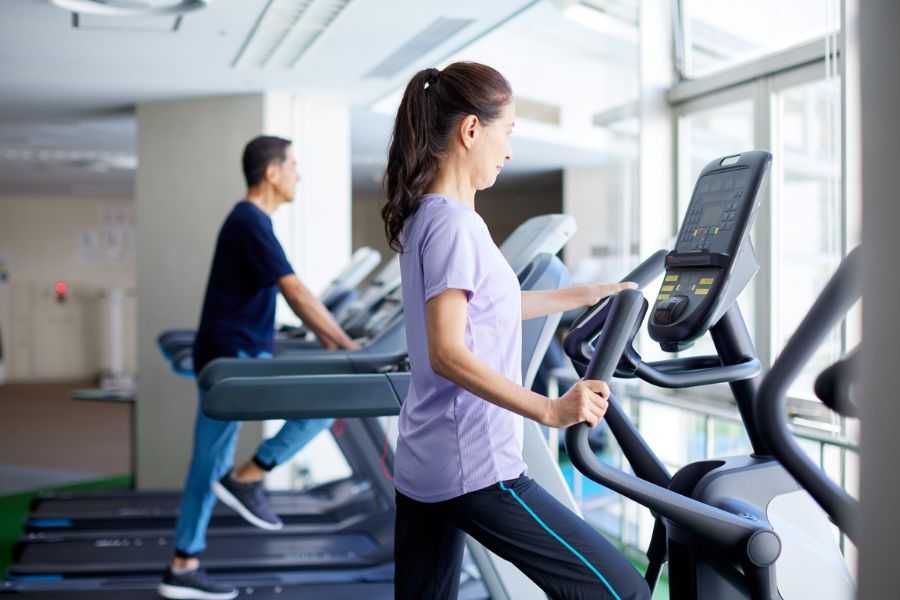 2 personas realizando ejercicio sobre caminadoras en un gimnasio