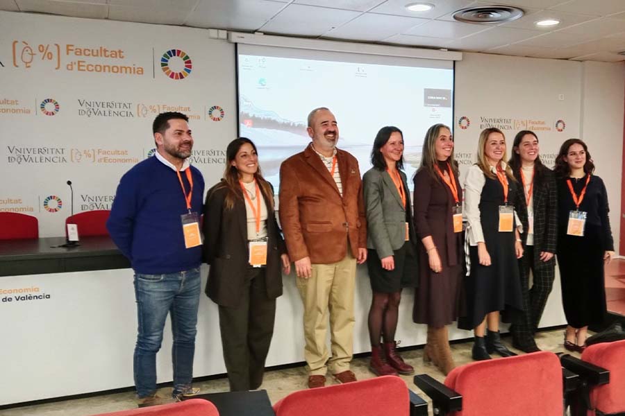 Un grupo de 8 investigadores posa al frente de un sal&oacute;n de congresos.