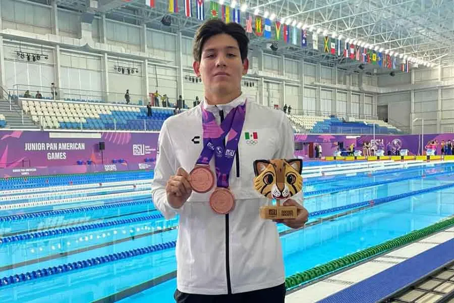 Deportista enseñando dos medallas y un trofeo de natación.