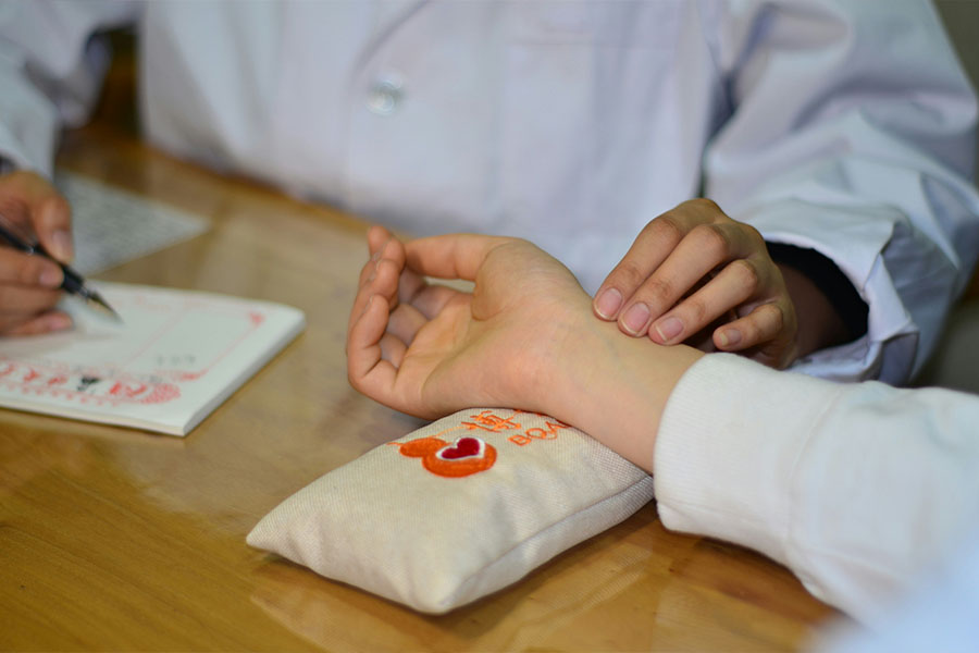Acercamiento a las manos de un doctor mientras revisa el pulso en la mu&ntilde;eca de un paciente.