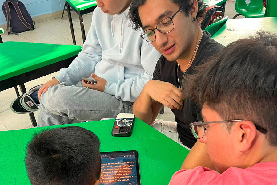 Emmanuel instruyendo a niños de una escuela primaria a usar KidTales.