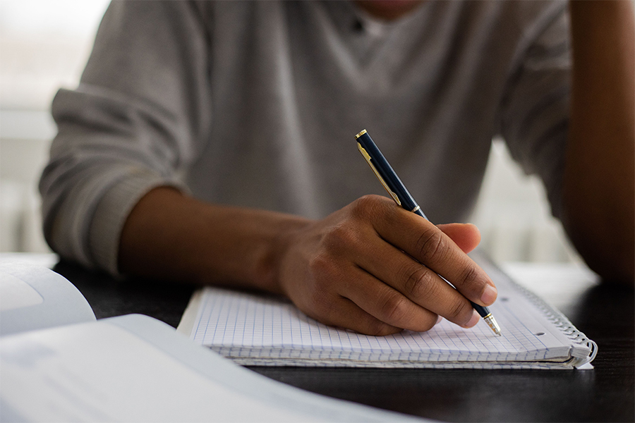 Estudiante escribiendo en cuaderno durante semestre escolar.