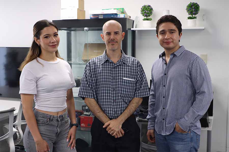 Foto de dos estudiantes de ingenier&iacute;a posando con su profesor. 