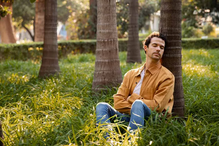 hombre durmiendo a lado de una palmera