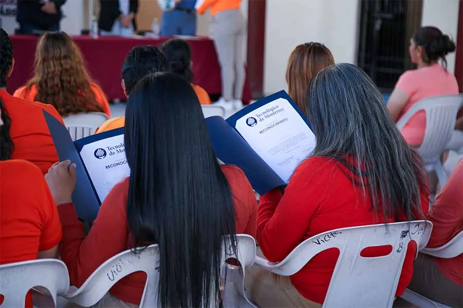Vista de espalda de dos mujeres viendo sus reconocimientos por graduarse de un curso.