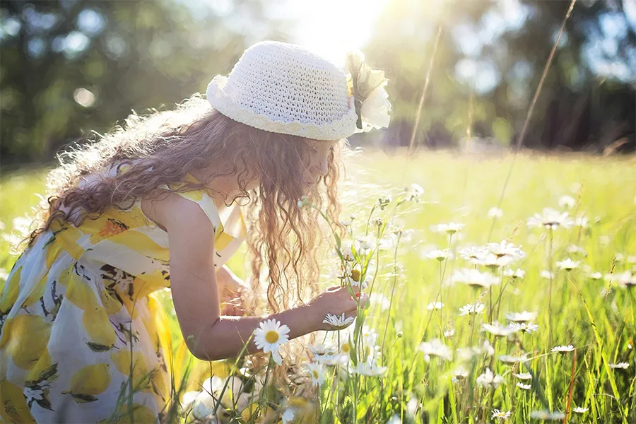 Niña oliendo flores