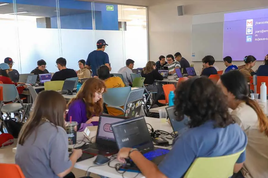 Salón lleno de estudiantes trabajando en sus computadoras.